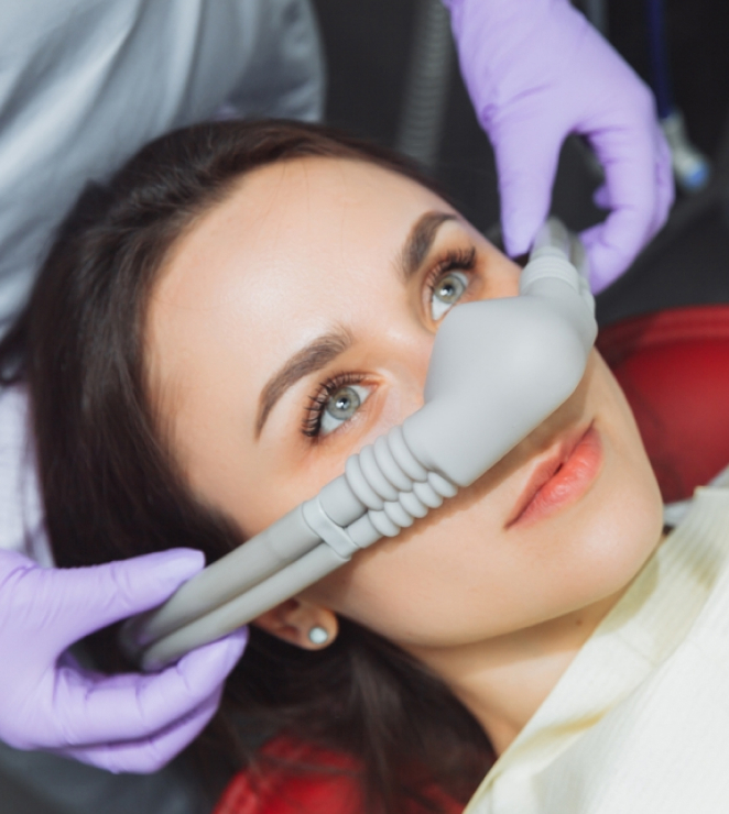 Patient receiving intravenous sedation dentistry treatment with dental professional administering anesthesia.